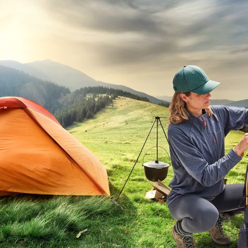 Woman outside tent in remote open countryside removing camping items from LayBakPak backpack