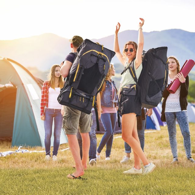 Two people with LayBakPak backpacks arrive at the camping area of a music festival