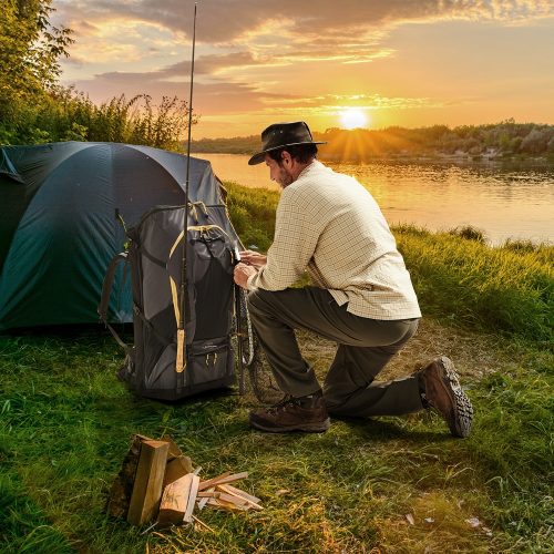 Man attaching fishing gear to his LayBakPak backpack ready for river fishing at sunset