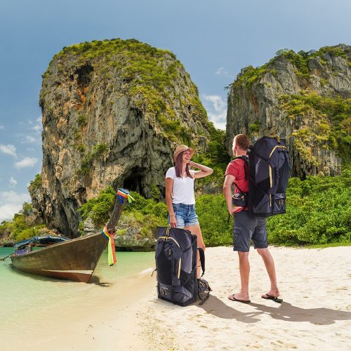 Two adventure travellers with fully loaded LayBakPak backpacks on tropical beach