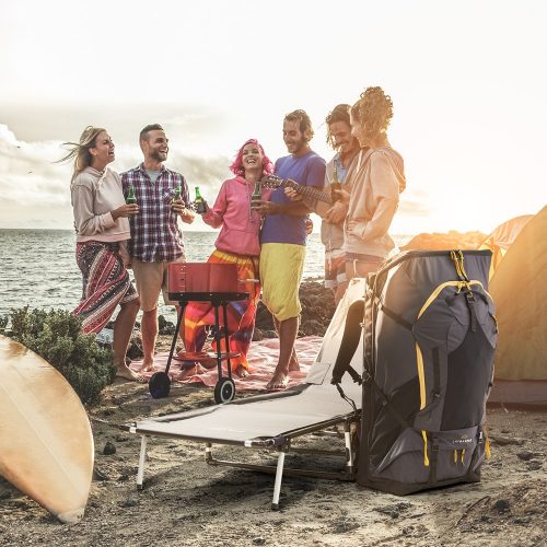 Group of people gathered round a barbecue on a beach with LayBakPak backpack and recliner camp bed in the foreground
