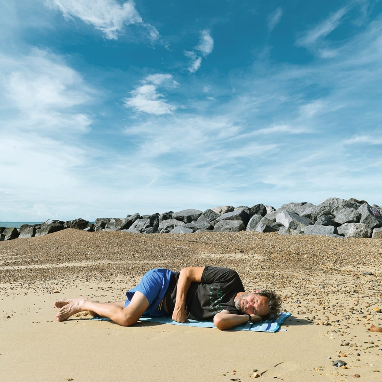 LayBakPak creator lying uncomfortably on a towel on a sandy beach