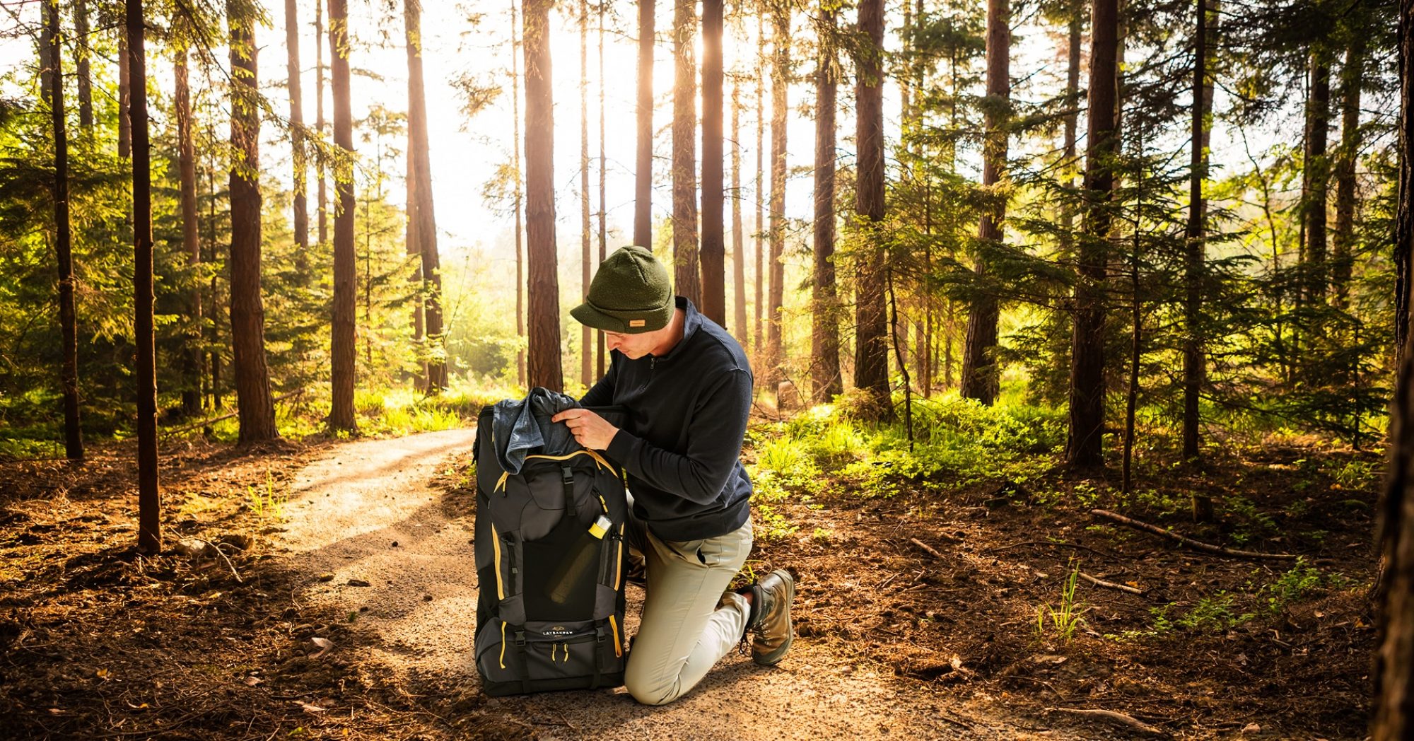 Man starting to unpack LayBakPak bag to set up camp in a woodland clearing