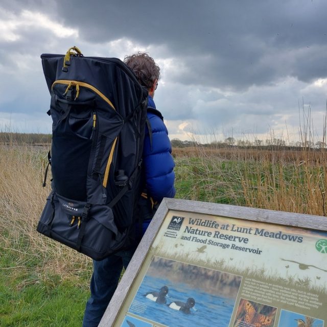 Man wearing LayBakPak backpack looking across the meadow land at Lunt Nature Reserve