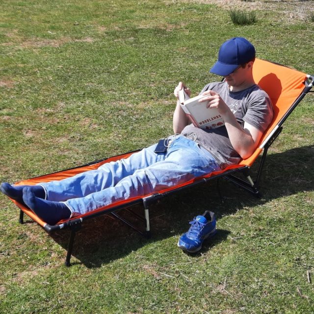 Man reading on LayBakPak bed in recliner position