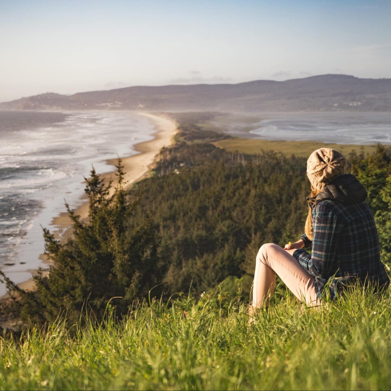 Girl listening to the sounds of nature whilst sitting on a hill overlooking sea